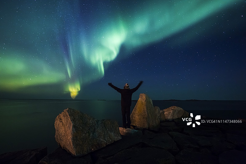 挪威，罗浮敦群岛，艾格姆，男人站在岩石上欣赏北极光的背影图片素材