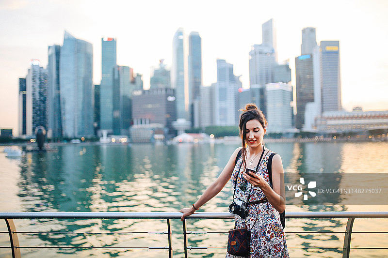 年轻时尚的女游客在新加坡看她的智能手机图片素材