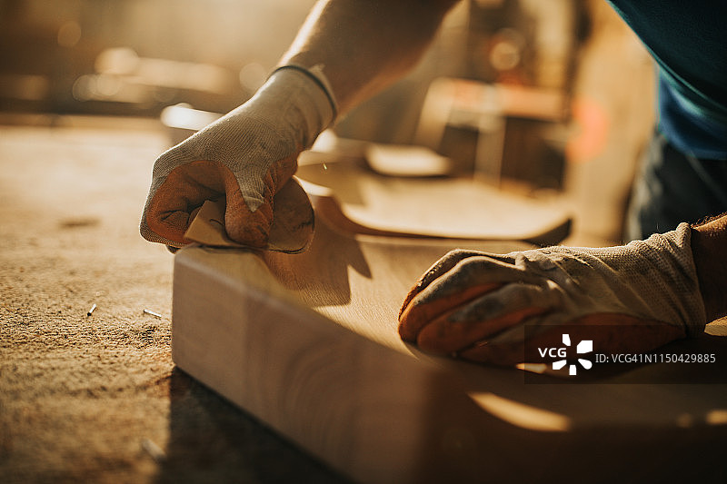 一个木匠用砂纸修复木材的特写。图片素材