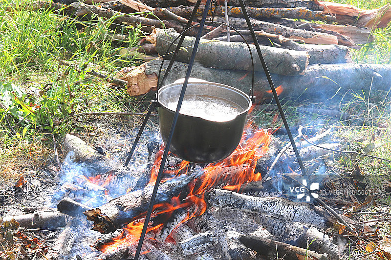 夏天在户外用铁锅在火上烹煮美味可口的食物图片素材