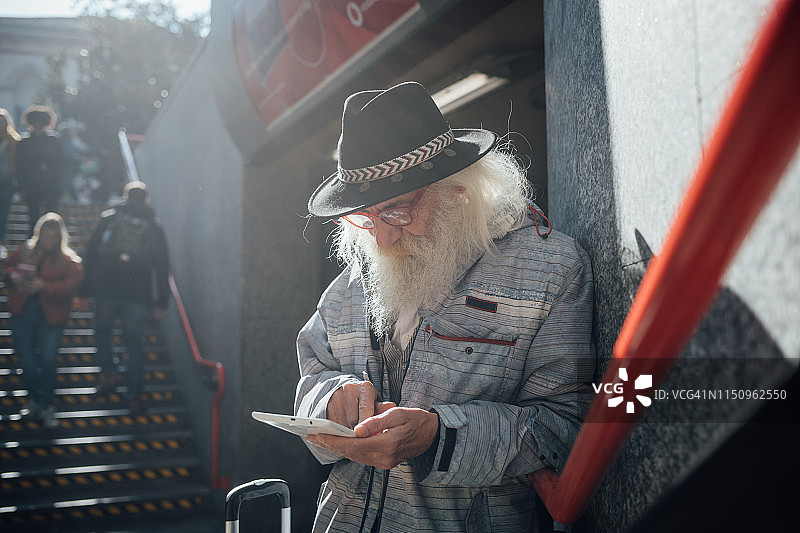 意大利伦巴第米兰，一名老年男子在地铁入口处使用平板电脑图片素材