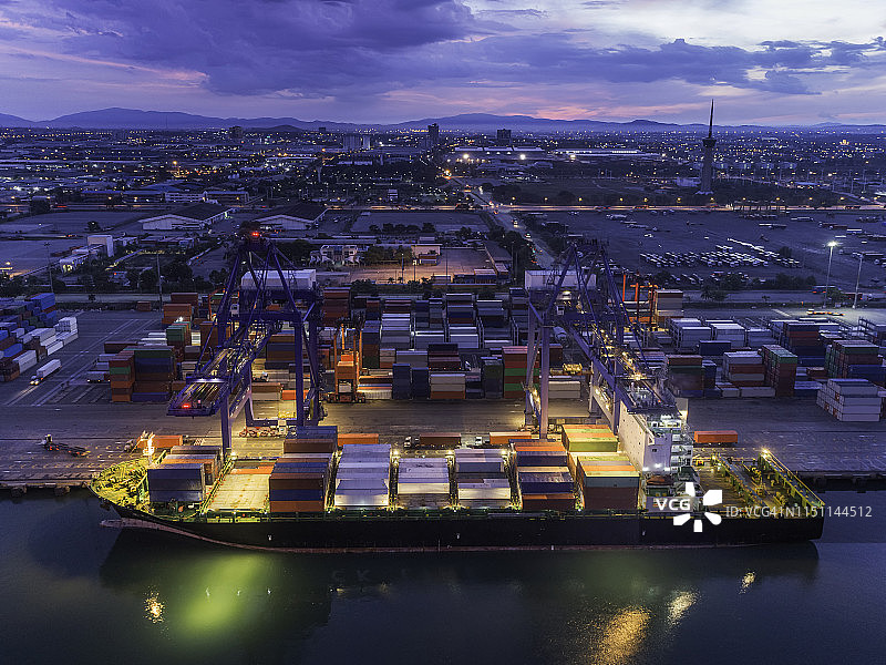 傍晚鸟瞰港口集装箱船，工作吊车桥装载集装箱用于物流、进出口、运输。图片素材