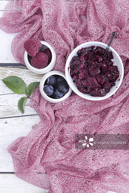 白碗里装着新鲜的野莓冰淇淋。配料上面的木材背景桌面上。直接在上面复制空间。图片素材