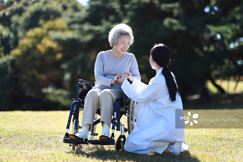 医生协助年长妇女在轮椅上图片素材