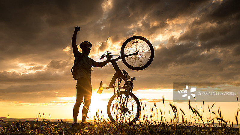 夕阳西下，一个骑自行车的人的剪影图片素材