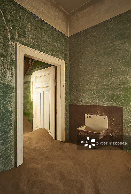 沙门口。绿色的墙壁与丰富的棕色沙子形成对比。纳米比亚，科尔曼斯科普鬼城的废弃房子。全彩色图像。图片素材