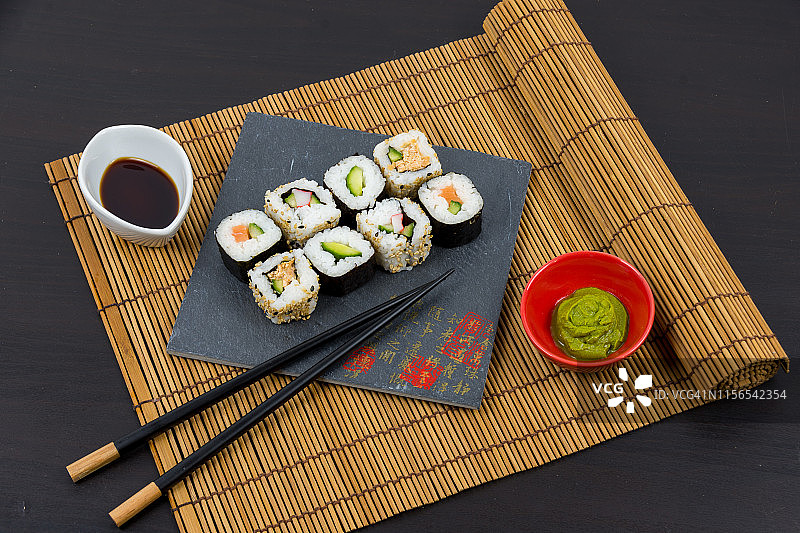 美味的寿司卷在黑石盘和酱油与芥末图片素材