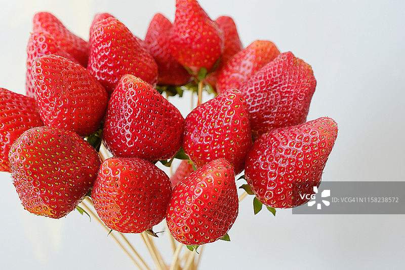 收集整个草莓果实木制串孤立在白色的背景。可选择可食用的浆果束，生日，情人节，节日，特写。有选择性的重点。图片素材