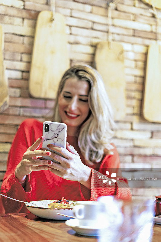 微笑的女人在咖啡馆用手机图片素材