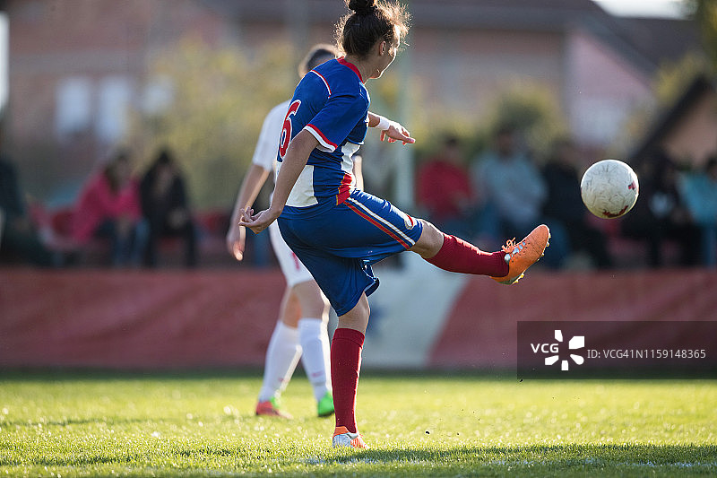 女足球运动员在比赛场上踢球。图片素材