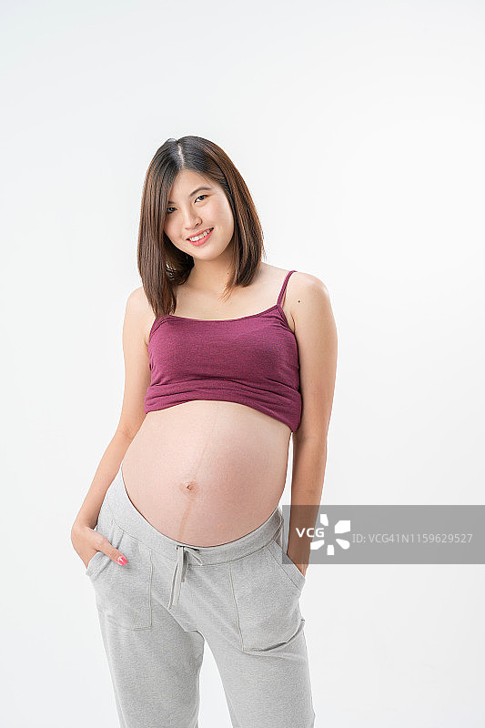 特写图像的怀孕亚洲妇女触摸她的腹部与手在白色的背景图片素材