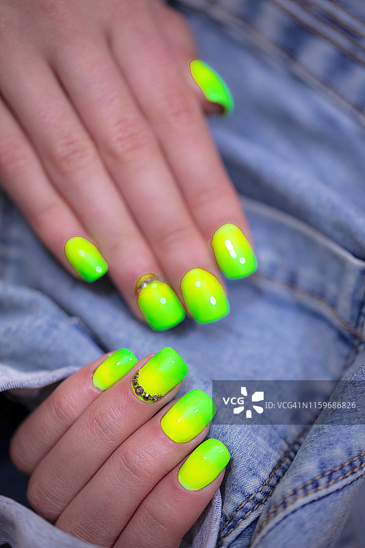 特写的女人的手指与指甲艺术美甲在霓虹灯绿色图片素材