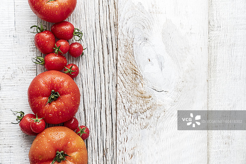 几个不同大小的西红柿放在一个白色的木盘子里图片素材