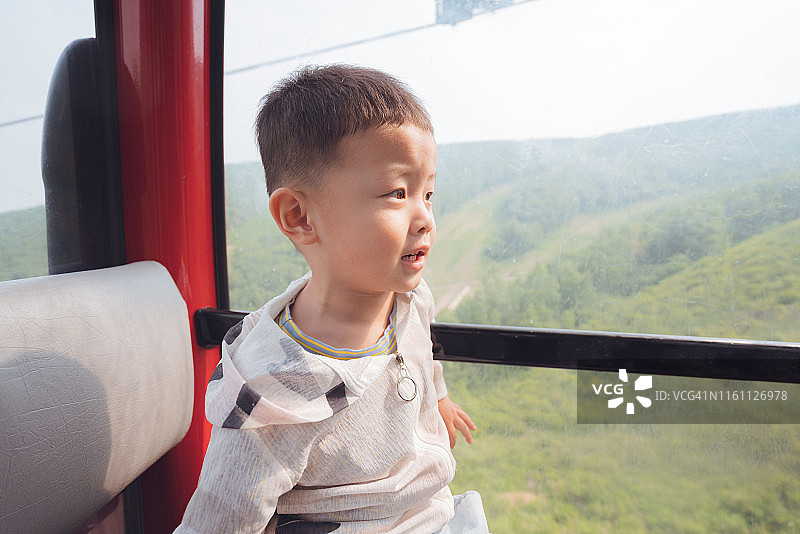 男孩在空中缆车上从窗户往外看图片素材