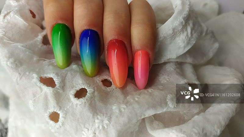 特写的女人的手指与指甲艺术美甲与霓虹灯彩虹的颜色图片素材