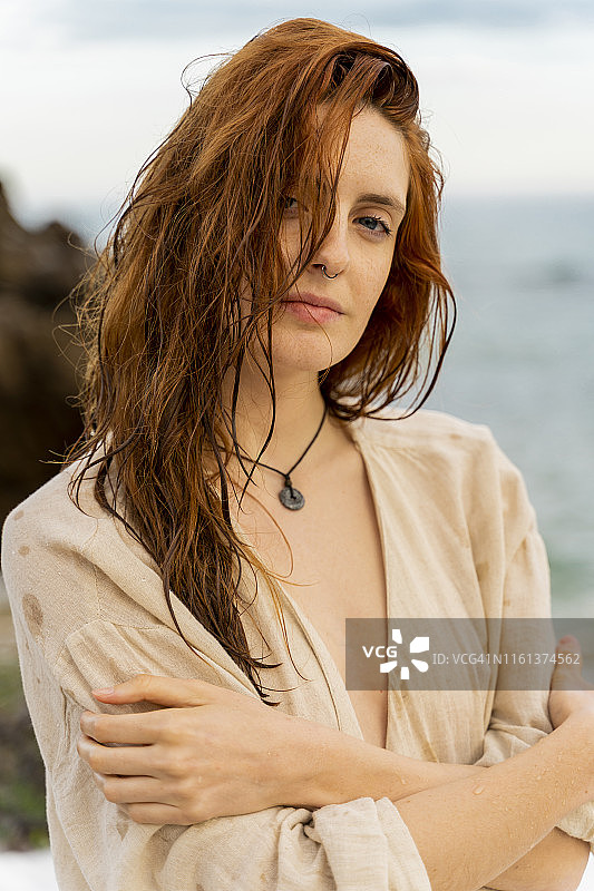 一幅红发年轻女子的肖像，在大海前穿鼻环图片素材