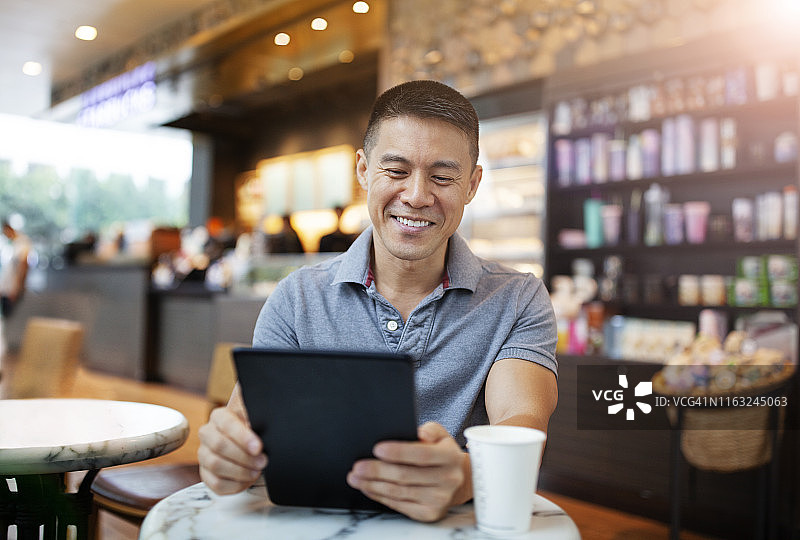 亚洲帅哥在咖啡厅用平板电脑图片素材