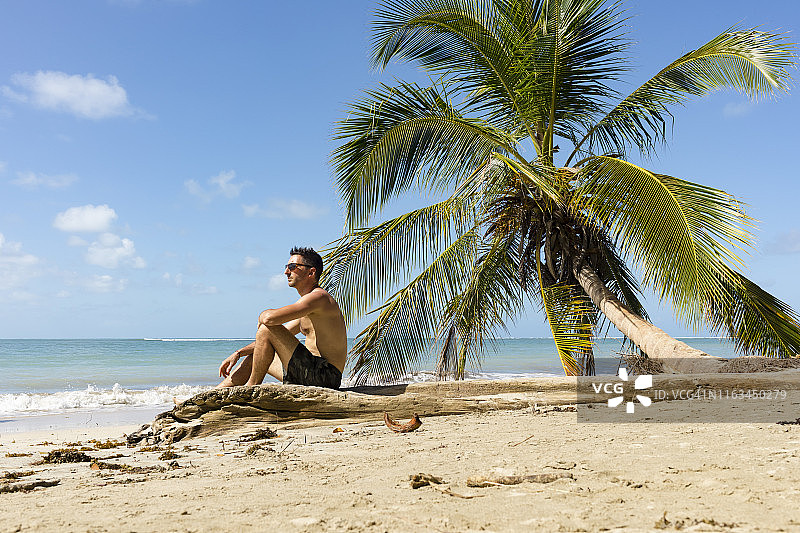 一名男子坐在哥斯达黎加卡胡塔国家公园的热带海滩上图片素材