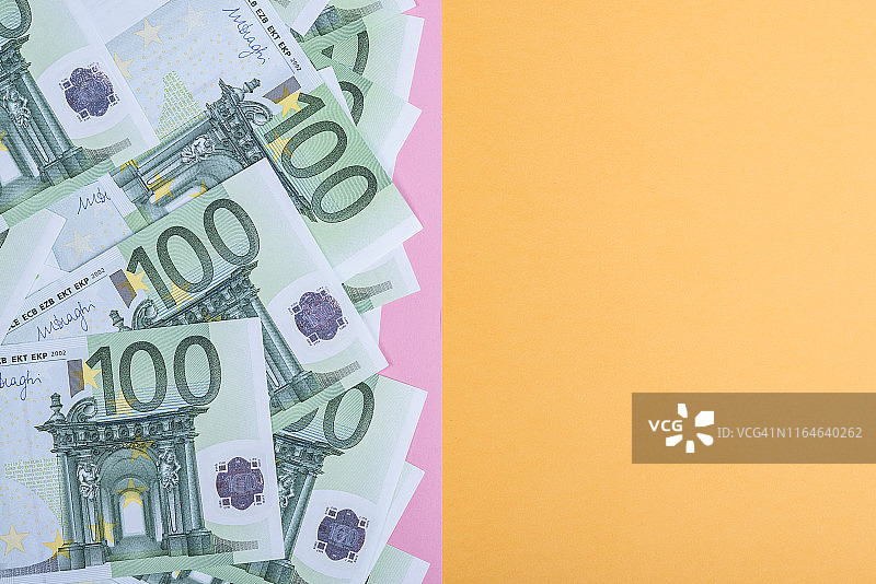 黄色和粉色背景的欧元现金。欧元纸币。欧元的钱。欧元的法案。文本。图片素材