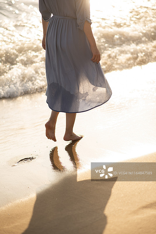 一个年轻女子在海滩上散步图片素材