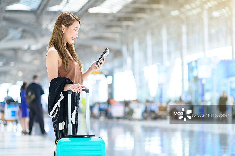 年轻的女商人在机场候机厅用手机手提行李图片素材
