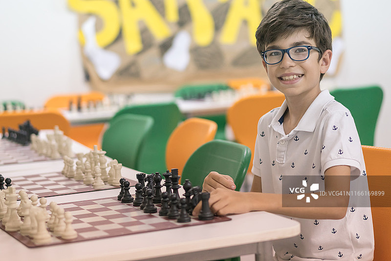 快乐的男孩在教室下棋图片素材