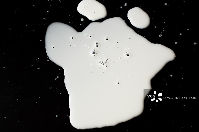 溢出的牛奶坑孤立的黑色背景和纹理与剪切路径，俯视图图片素材