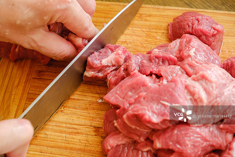 屠夫在厨房切猪肉。用刀切新鲜的肉。图片素材