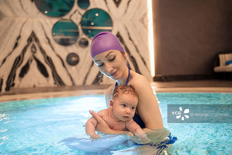 假期母亲和婴儿在游泳池游泳图片素材
