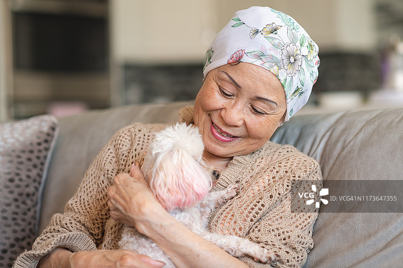 患有癌症的妇女在家里和她的宠物狗放松图片素材