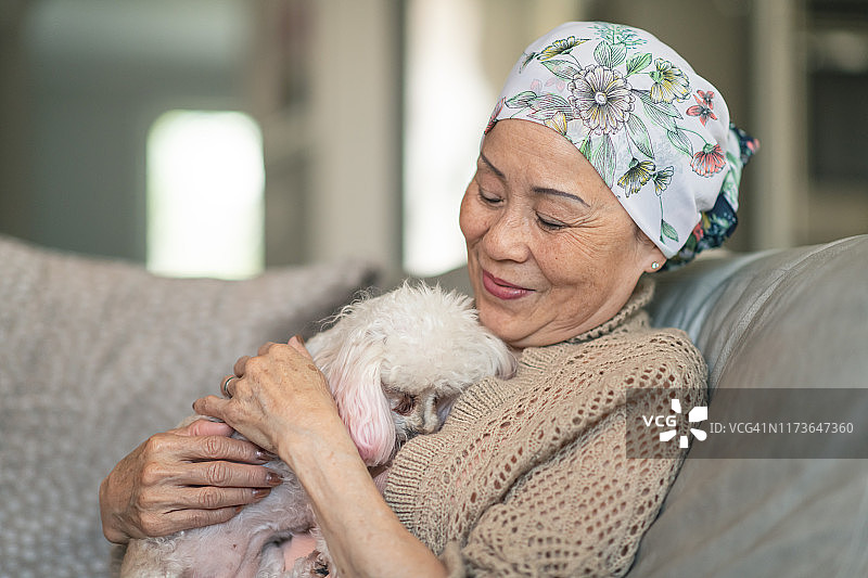 患有癌症的妇女在家里和她的宠物狗放松图片素材