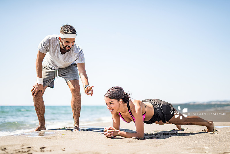 一对年轻夫妇在海滩上一起锻炼。图片素材
