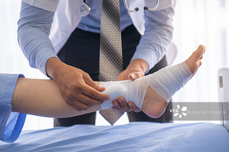 床上骨折患者，医生或理疗师给床上骨折患者进行专家治疗，使其恢复良好，有膝盖问题的患者在咨询室图片素材