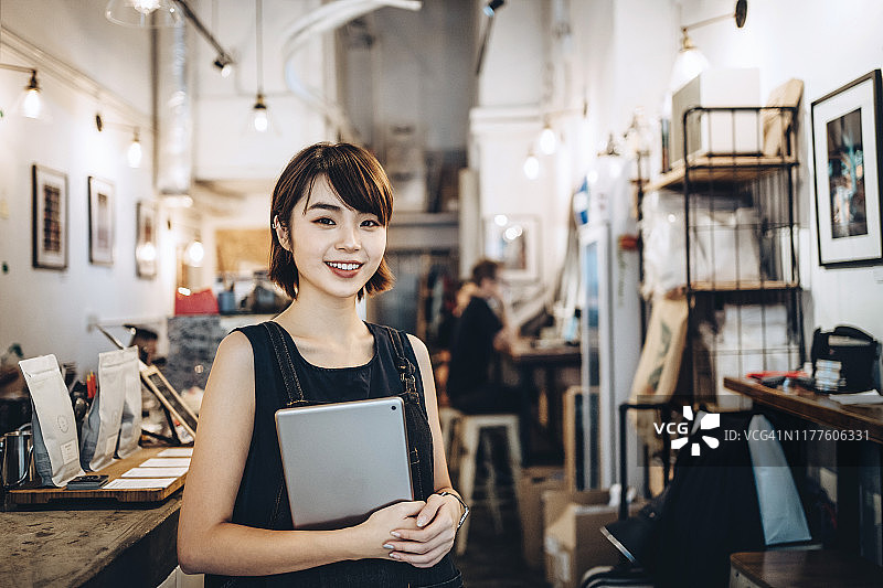 一个自信的年轻企业主在她的咖啡店里使用数字平板电脑的肖像图片素材