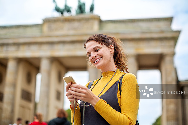 用手机对抗勃兰登堡门的快活女人图片素材