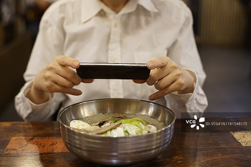 在韩国餐厅用智能手机拍照的女人图片素材