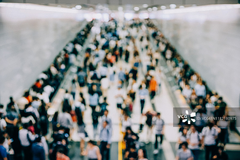 在城市的办公高峰期，繁忙的通勤者走过地铁站的平台图片素材