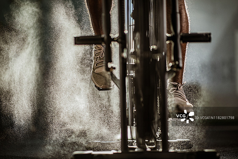 一个不知名的男性运动员在健身房里的固定自行车上锻炼。图片素材
