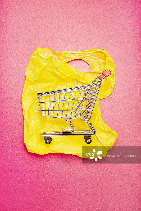 粉红色背景的塑料袋上的小购物车图片素材