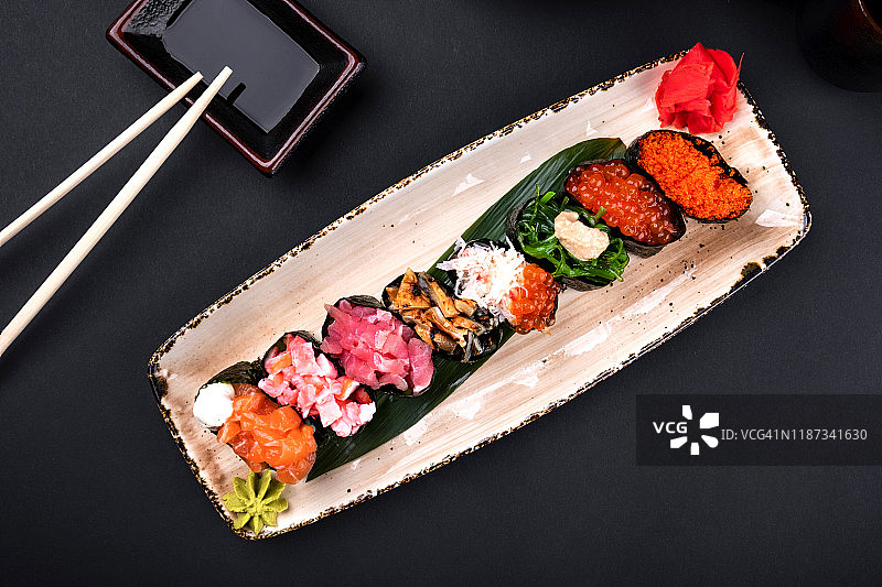 俯视图近距离的生鱼片寿司与筷子和大豆在黑色的背景。韩国卷，绿茶杯和茶壶，复印空间。日本的食物。图片素材
