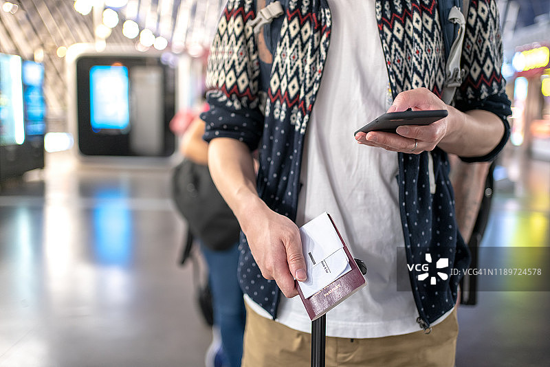 一名男子正在机场排队，一手拿着护照，一手拿着手机图片素材