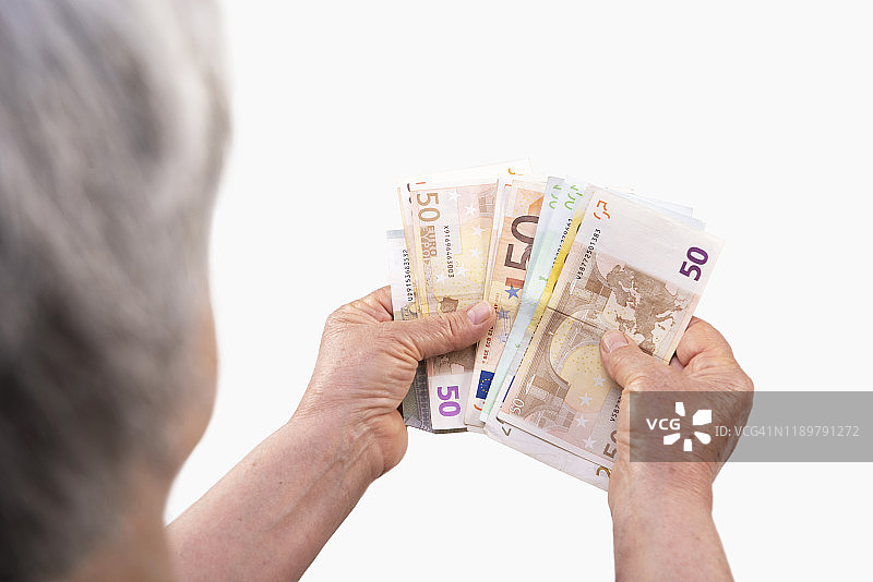 在灰色背景下，高角度的老妇人在数欧元钞票图片素材