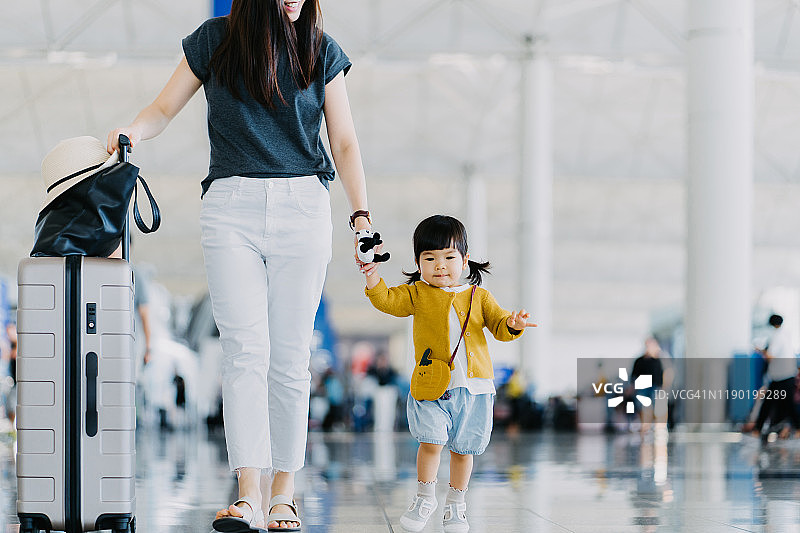 快乐的年轻亚洲母亲与可爱的小女儿乘飞机度假，而走过机场大厅图片素材