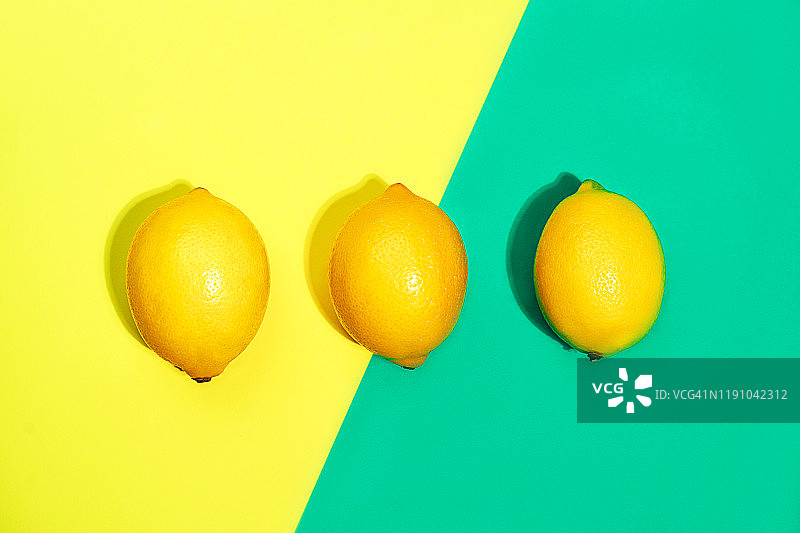 柠檬的创意图案，明亮的黄色和时尚的绿蓝色背景。图片素材
