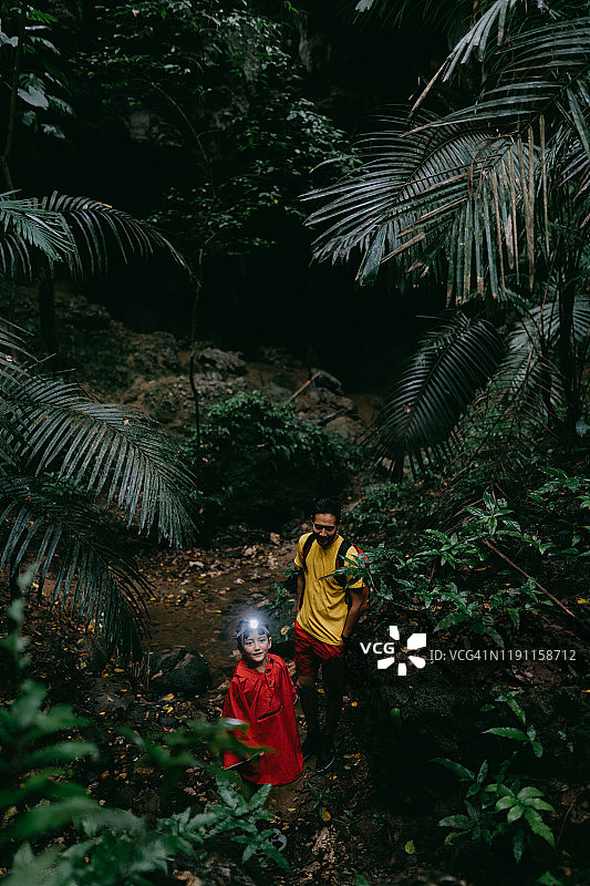 小女孩带着头灯和父亲徒步穿过丛林洞穴，Iriomote，冲绳，日本图片素材