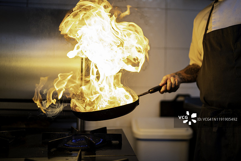 厨师在商业厨房用平底锅准备火焰粉图片素材