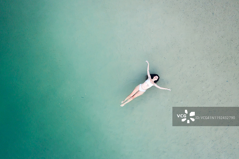 一个女人躺着，漂浮在浅水里的鸟瞰图图片素材