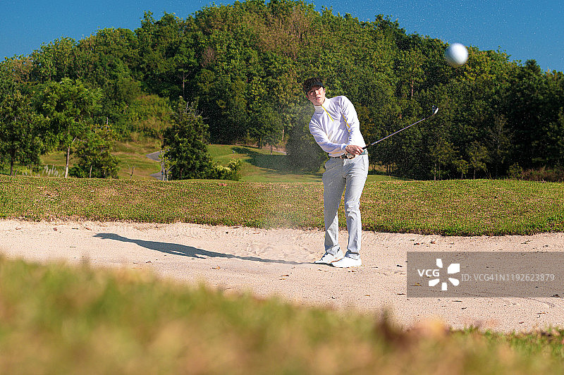 高尔夫球手在沙坑中挥杆图片素材