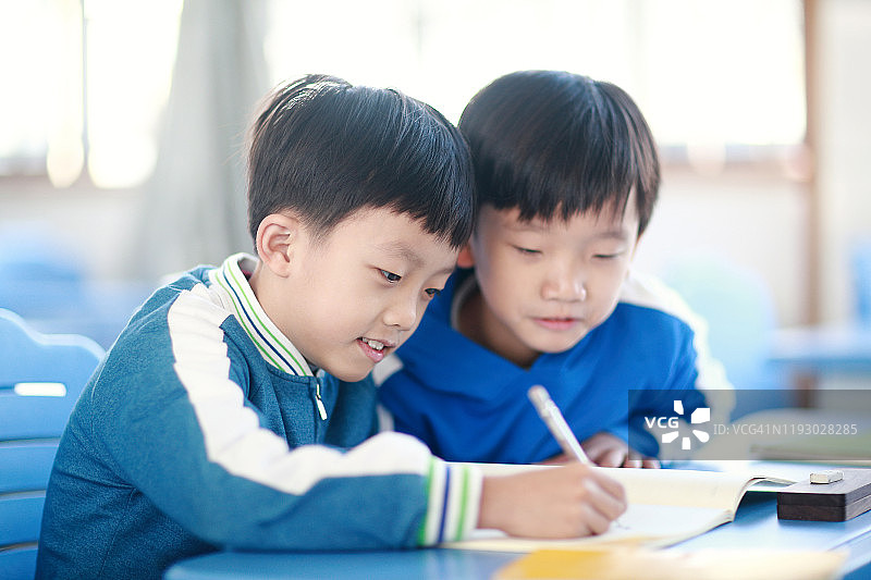 小男孩在教室里的书桌前读书图片素材