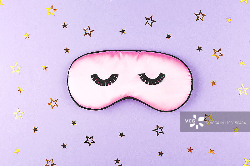 可爱的粉色睡眠面膜在紫色的背景。图片素材